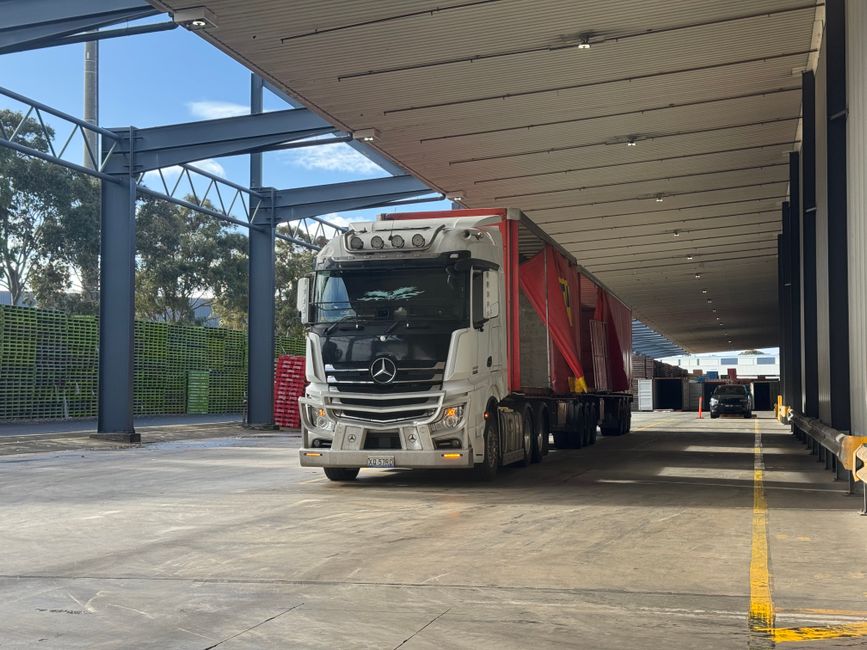 Large truck parked in a loading bay under a roof, ready for industrial transport.